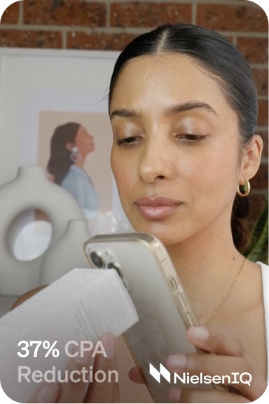 A woman holding a cell phone with a box of makeup.