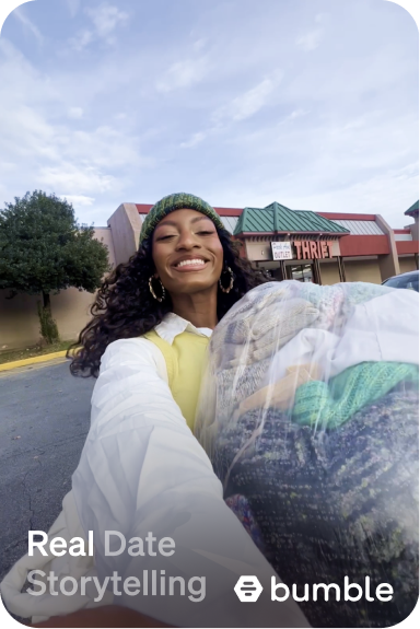 A woman with a green hat and yellow shirt is holding a bag of clothes.